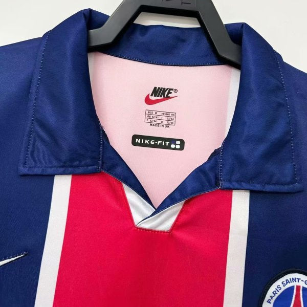 Blue, red, and white psg 98/99 home shirt with Nike branding on a hanger against a light gray background.