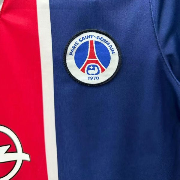 Close-up of a Paris Saint-Germain logo on a psg 98/99 home shirt  with red and white accents.