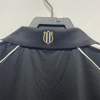 Newcastle 00/01 away shirt with a logo on a hanger against a white background