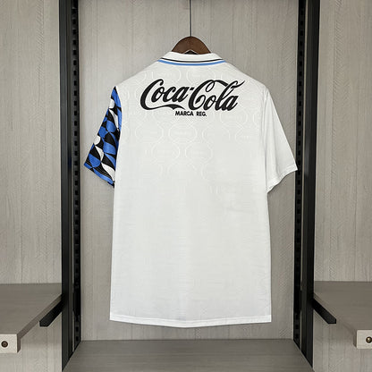 White Gremio 94/95 away shirt with Coca-Cola logo on a hanger against a neutral background