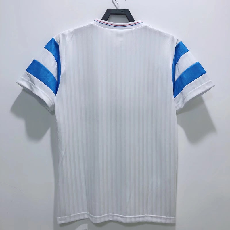 White Marseille 90/91 home shirt with blue accents on a hanger against a white background