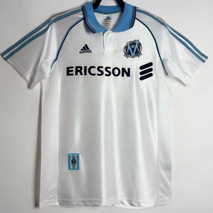 White Marseille 98/99 centenary home shirt with blue accents and Adidas logo on a white background