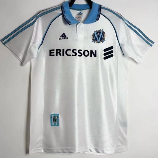 White Marseille 98/99 centenary home shirt with blue accents and Adidas logo on a white background