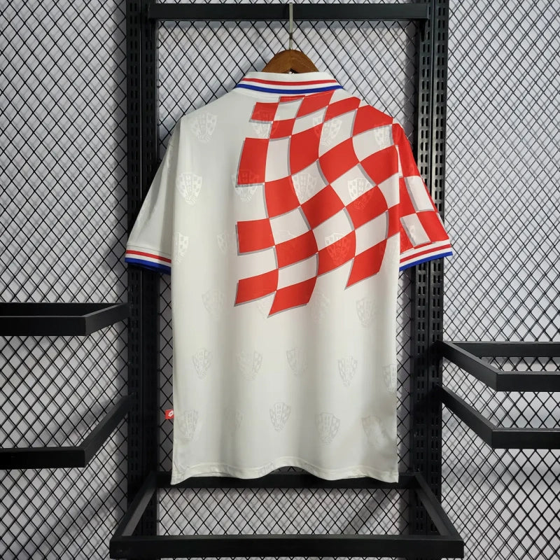 White Croatia 1998 home shirt  with red and blue checkered design on a hanger against a black metal rack.
