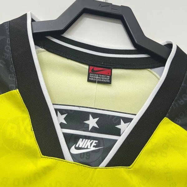 Yellow and black Nike Dortmund 94/95 home shirt  on a hanger against a white background
