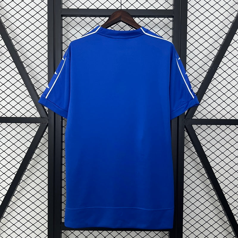 Blue Juventus 99/00 away shirt  hanging against a black metal grid background