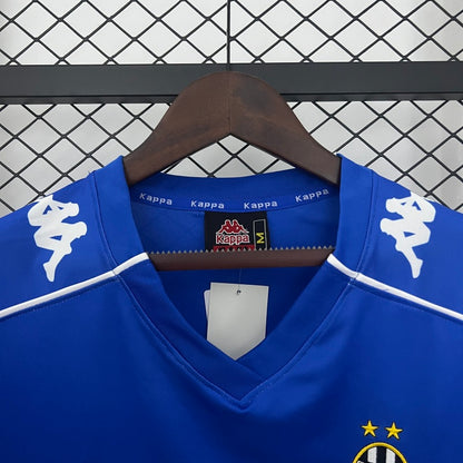 Blue Juventus 99/00 away shirt  with white accents on a hanger against a checkered background