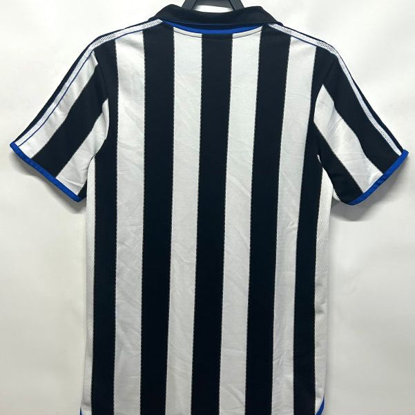 Black and white striped Newcastle 00/01 home shirt on a hanger against a white background