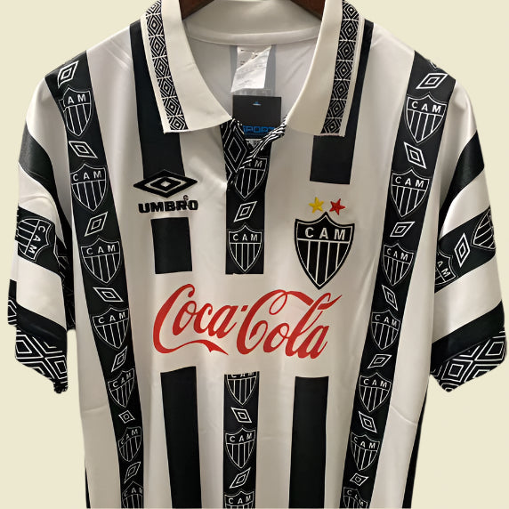 Black and white striped Mineiro 94/95 home shirt with Coca-Cola logo on a gray background
