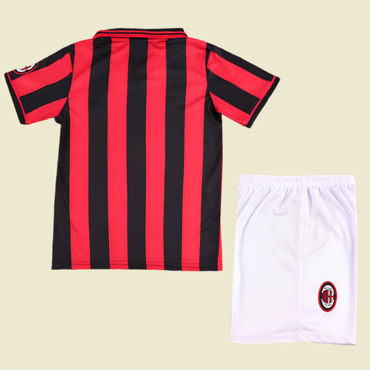 Black and red striped ac Milan 96/97 kids kit with white shorts on a textured gray background