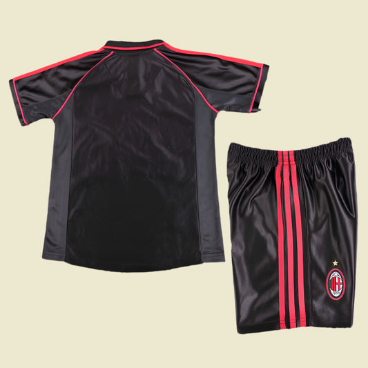 ac Milan 98/99 third kids kit  with red accents on a textured gray surface