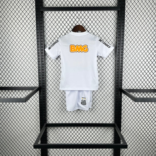 White Santos 2012 centenary home kids kit with orange logo on a black metal rack against a gray wall.