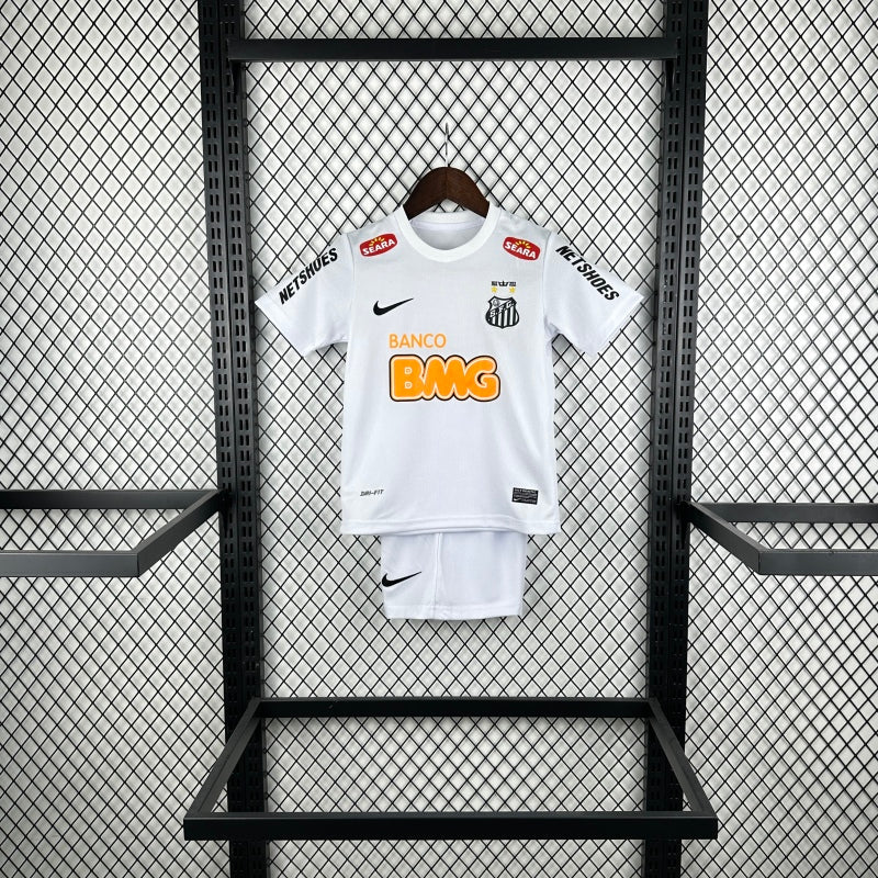 White Santos 2012 centenary home kids kit with branding on a black metal rack against a patterned wall.