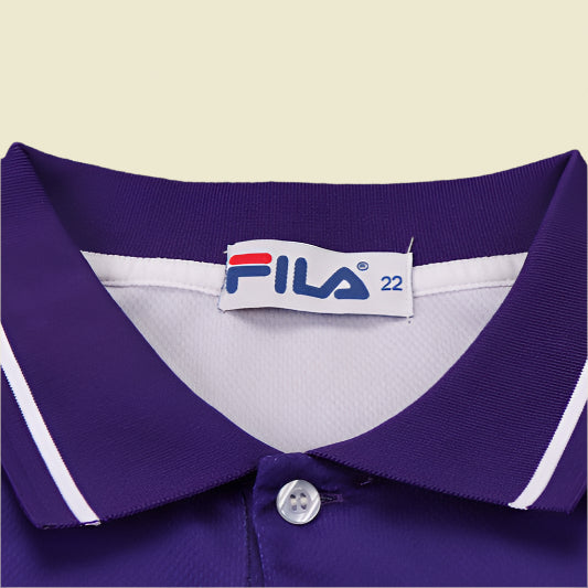Close-up of a purple Fiorentina 99/00 home kids kit  with a Fila label on a textured gray background
