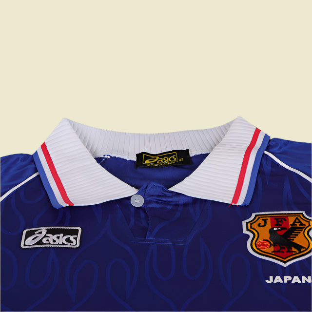 Blue Japan 1998 home kids kit with white collar and JFA logo on a textured gray background