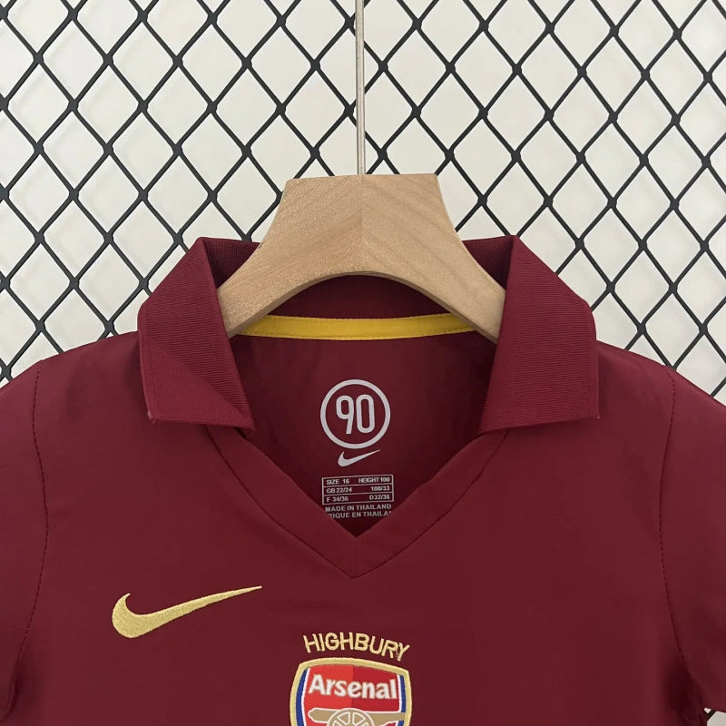 Maroon Arsenal 05/06 commemorative Highbury home kids kit on a hanger against a wire mesh background