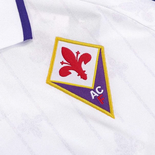 Close-up of a Fiorentina 97/98 away shirt  with a logo featuring a red emblem and 'AC' text on a white background.