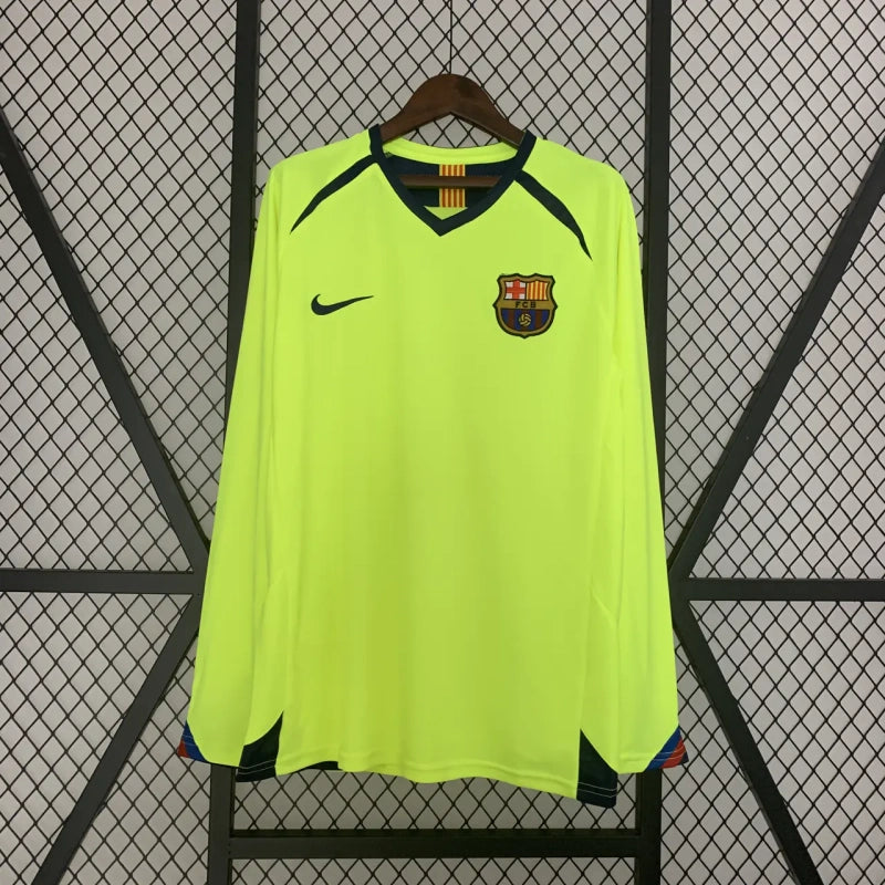 Fluorescent green Barcelona 05/06 long sleeve away shirt with a logo on a hanger against a wire mesh background