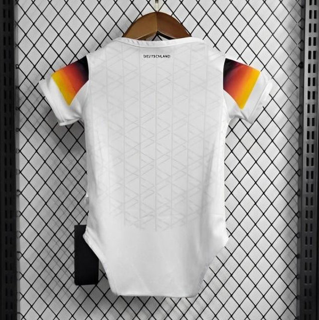White Germany 2024 home baby onesie  with colorful design on a hanger against a grid-patterned wall.