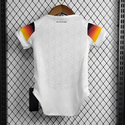 White Germany 2024 home baby onesie  with colorful design on a hanger against a grid-patterned wall.