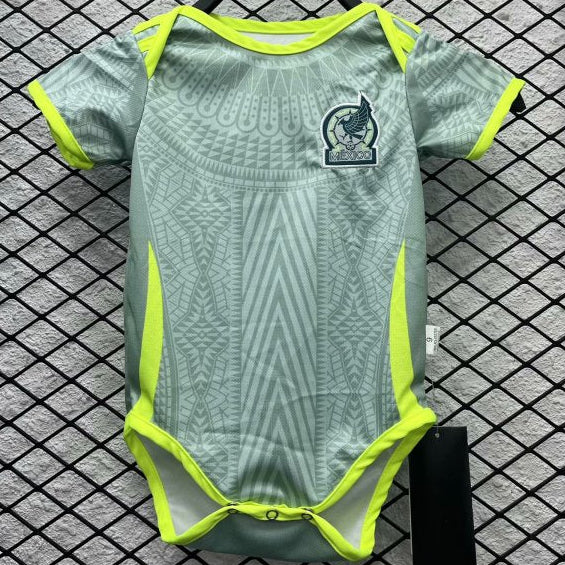 Green and yellow Mexico 2024 away baby onesie  with a logo on a hanger against a checkered background