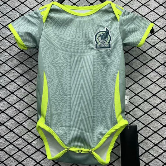 Green and yellow Mexico 2024 away baby onesie  with a logo on a hanger against a checkered background