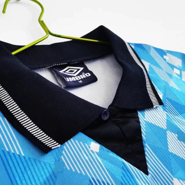 Black collar England 1990 third shirt with Umbro logo on a blue patterned fabric background