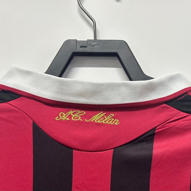 Black and red striped Ac Milan 09/10 long sleeve home shirt  with 'A.C. Milan' logo on a hanger against a white background