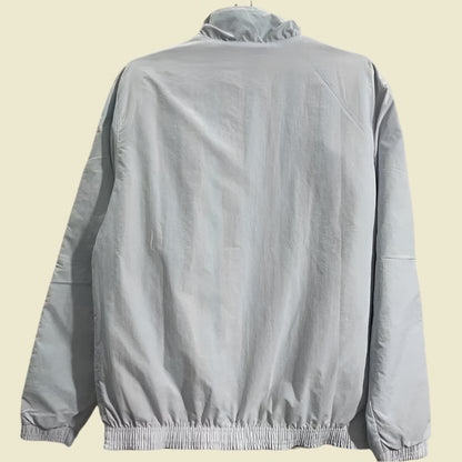 Light gray Ac Milan 2010’s windbreaker jacket  on a hanger against a plain background